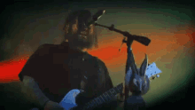 a man playing a guitar and singing into a microphone .