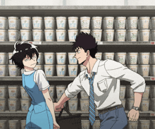 a man and a woman are standing in front of a shelf of cups that say y12 on them