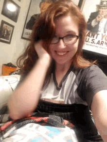 a woman wearing glasses is laying on a bed in front of a poster that says army
