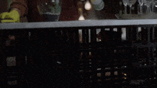 a woman wearing yellow rubber gloves is cleaning a glass on a counter