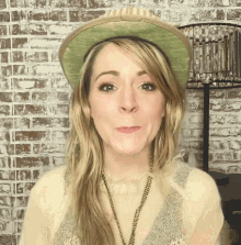 a woman wearing a hat and a necklace makes a face