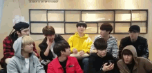 a group of young men are sitting in a room with a sign that says leader in entertainment