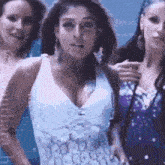 a group of three women are standing next to each other . one of the women is wearing a white tank top .