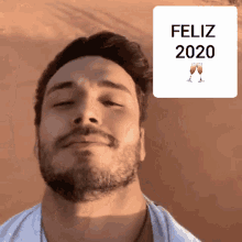a man with a beard stands in front of a feliz 2020 sign