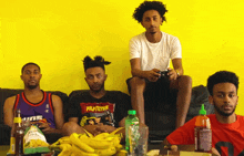 a man wearing a pulp fiction shirt sits on a couch with two other men