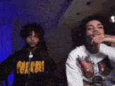 a man wearing a hoodie that says peace on it stands next to another man
