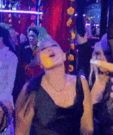 a woman in a black dress is dancing in a crowd of people .