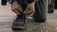 a person kneeling down tying their shoelaces with a long walk logo in the corner