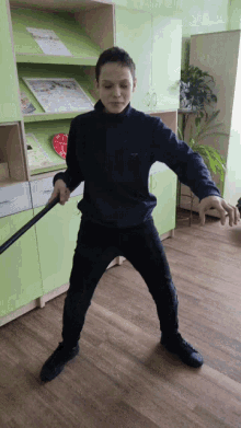 a boy is holding a stick in front of a green cabinet