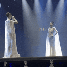 a woman taking a picture of another woman on a stage with the word phu in the background