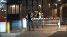 two security guards are standing behind a red and white barrier