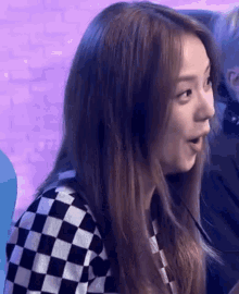 a woman is wearing a black and white checkered sweater and making a surprised face .