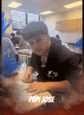 a young man sits at a desk with the name papi jose written on the bottom
