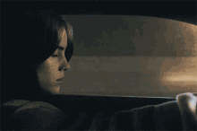 a woman is sitting in a car looking out the window