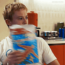 a boy is holding a bag of cereal in front of his face and the words joequinngraves are on the bottom right
