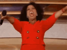 a woman in a red jacket is screaming into a microphone .