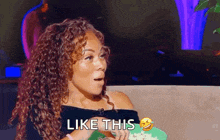 a woman with curly hair says like this while holding a plate of popcorn