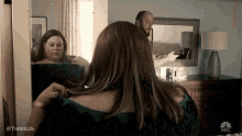 a man is touching a woman 's hair in front of a mirror in a bedroom .