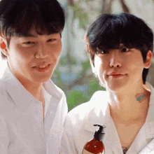 two men are standing next to each other and one of them is holding a bottle of liquid