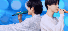 two men are singing into microphones while standing next to each other