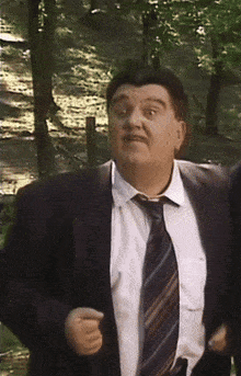 a man in a suit and tie stands in a forest