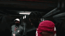 a football player in a red uniform is putting on his helmet .