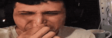 a man is laughing and covering his mouth with his hand .