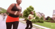 a woman is jogging down a street while another woman looks on .