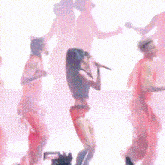 a woman singing into a microphone while a man dances behind her