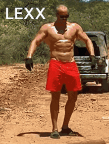 a shirtless man in red shorts is standing in the dirt with lexx written in white letters
