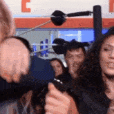 a woman is holding a cell phone in front of a crowd of people in a boxing ring .