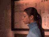a woman wearing a blue turtleneck sweater and earrings