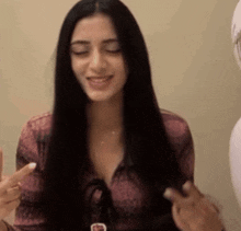 a woman with long black hair is smiling and holding her hair