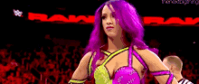 a woman with purple hair is standing in front of a crowd of people .