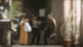 a blurry picture of people in a room with a plant in the foreground