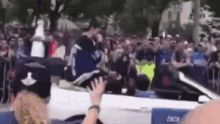 a crowd of people are gathered around a white car with the word crew on the side