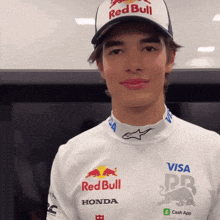 a young man wears a red bull hat and a white shirt