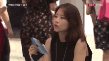 a woman is holding a fan in front of a screen that says ytn on it