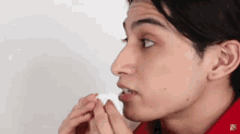 a man in a red shirt is blowing his nose into a tissue