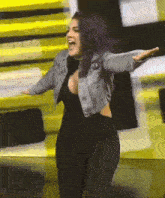a woman with purple hair is wearing a denim jacket