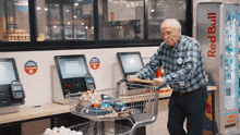 an elderly man pushes a shopping cart in front of a red bull machine