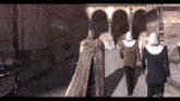 a man in a cape is walking with two nuns
