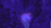 a person is touching a woman 's face in a dark room with a purple light coming out of it .