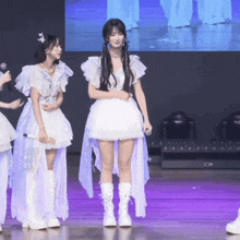 a woman in a white dress stands next to another woman
