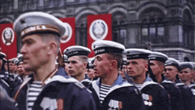 a group of men in military uniforms are marching in front of a building with a red banner that says cccp
