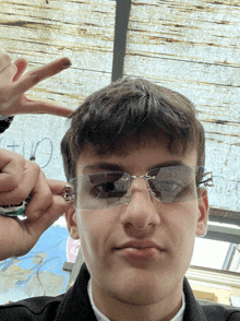 a young man wearing a pair of sunglasses is making a peace sign