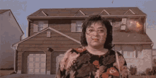 a woman is standing in front of a house that is on fire