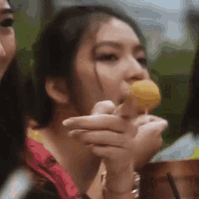 a woman is eating a donut on a stick while sitting at a table .