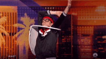 a man wearing glasses and a red headband is holding a shield over his head on a stage .