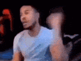 a man in a white shirt is dancing in a dark room with a blurry background .